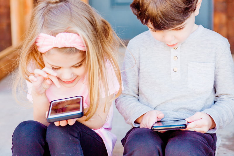 Girl and play sitting and playing with smartphones.