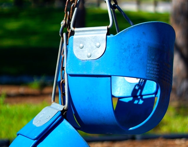 Two blue child playground swings locked together during the pandemic / COVID 19.